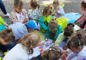 Dzieci w grupach wyklejają kolorowym papierem numer swojej grupy.