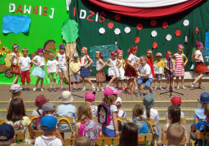 Dzieci śpiewają i tańczą Krakowiaka.