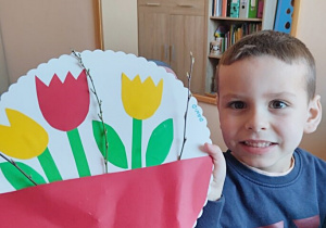 Chłopiec prezentuje zrobione wiosenne kwiaty.