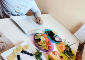 Dziewczynka przygotowuje pracę na talerzu z owoców.