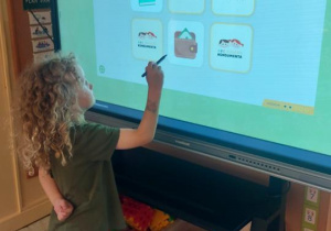 Dzieci grają w grę Sklepowe Memo na monitorze dotykowym.