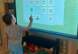Dzieci grają w grę Sklepowe Memo na monitorze dotykowym.
