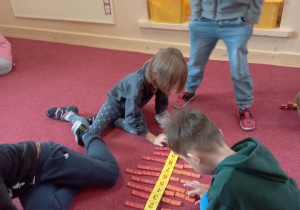 Dzieci przeliczają kropki na kostkach domina i układają przy właściwej cyfrze.
