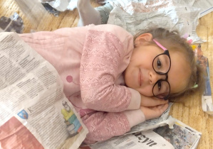 Dziewczynka bawi się gazetami.