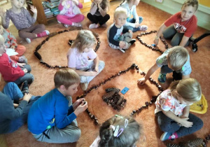Dzieci układają figury z kasztanów.