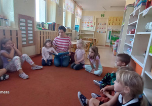 Dzieci słuchają opowiadania czytanego przez mamę dziewczynki.