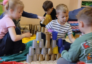 Dzieci układają wieże z kubeczków.