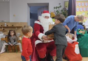 Mikołaj wręcza prezenty chłopcu.