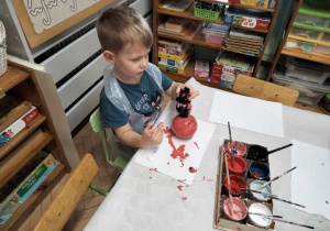 Chłopiec maluje bałwankową bombkę.