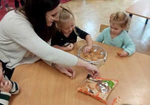 Dzieci układają ciasteczka w foremce wraz z mamą.