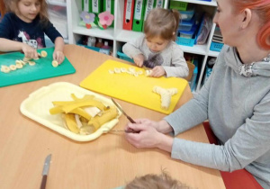 Dzieci kroją banany wspólnie z mamą.