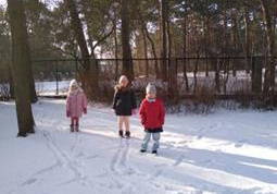 Dzieci bawią się na śniegu w ogrodzie przedszkolnym.