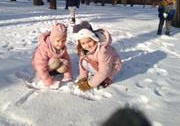 Dziewczynki bawią się na śniegu w ogrodzie przedszkolnym.
