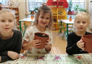 Dzieci z doniczkami zasadzonych kwiatów.