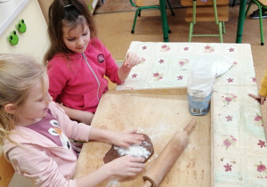 Dzieci wałkują ciasto na pierniczki.