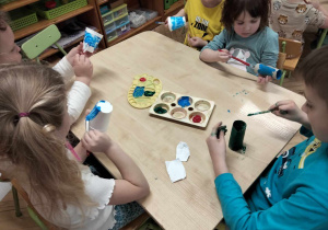 Dzieci malują kubeczki, z których zrobione zostaną wiatraczki.