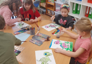 Malowanie farbami wesołych dinozaurów.