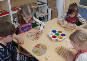 Dzieci malują pisanki ozdobione makaronem.