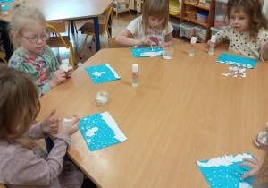 Dzieci tworzą zimowy pejzaż wydzierając biały papier.