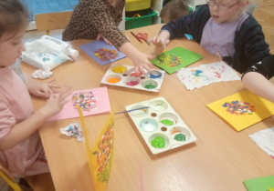 Dziewczynki malują palcami bukietowe laurki.