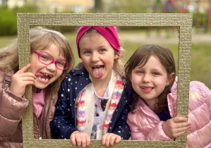Dziewczynki tworzą portret w złotej ramie.
