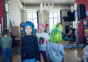 Dzieci przymierzają kolorowe peruki w Teatrze Wielkim.