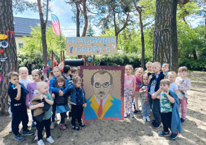 Zdjęcie grupowe w ogrodzie z wizerunkiem malarza.