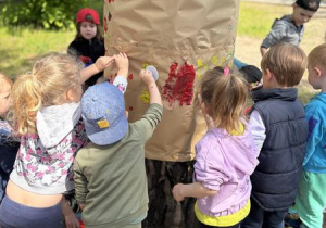 Dzieci malują na drzewie w trakcie dnia twórczości.