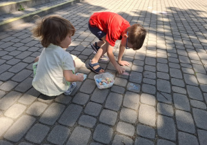 Dzieci rysują kredą po kostce.