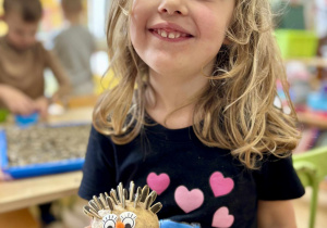 Dziewczynka pokazuje zrobionego jeża z ziemniaka.