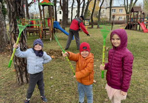 Dzieci grabią liście w ogrodzie.