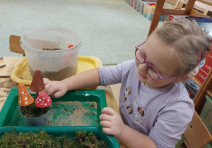 Dziewczynka maluje sylwety grzybów.