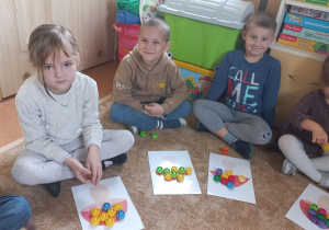 Dzieci przeliczają kolorowe zakrętki.