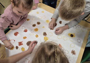 Dzieci tworzą drzewo jesienne - odrysowują kasztany i zamalowują je.