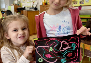 Dziewczynki prezentują pracę z nitek.