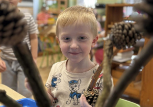 Chłopiec maluje szyszki.