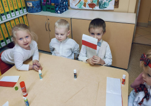 Dzieci tworzą flagę Polski z biało-czerwonych pasków.