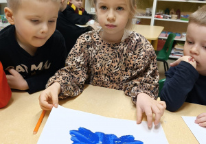 Dziewczynka pokazuje wróżbę, która powstała z plamy farby.