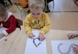 Chłopiec wykleja literę plasteliną.