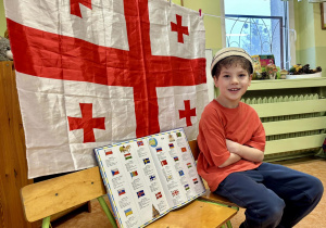 Chłopiec prezentuje atlas flag.