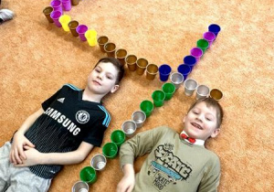 Chłopcy układają cyfrę 4 z kubeczków.