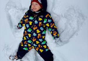 Chłopiec robi orła na śniegu.