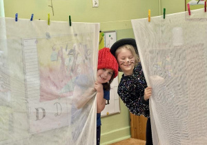 Dziewczynki wyglądają za zasłony.