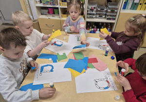 Dzieci wyklejają papierem literkę a.
