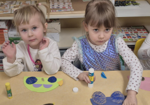 Młodsze dzieci przyklejają wycięte koła do złożonych aut.