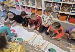 Dzieci wspólnie przykleją i ulicę na dużym papierze.