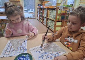 Dzieci malują pejzaż zimowy.