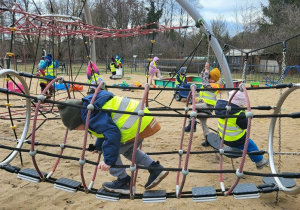 Dzieci wspinają się po drabinkach na placu zabaw.