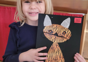 Dziewczynka prezentuje prace plastyczną "Kot".