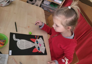 Dziewczynka wykonuje kota z papieru.